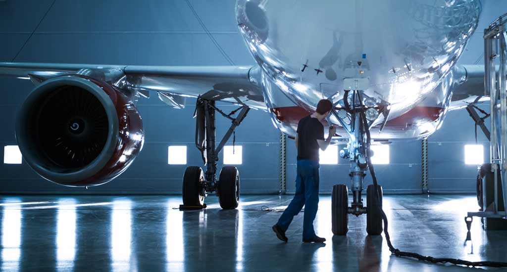 An engineer checking tubes in control rods and transmission systems on an aeroplane